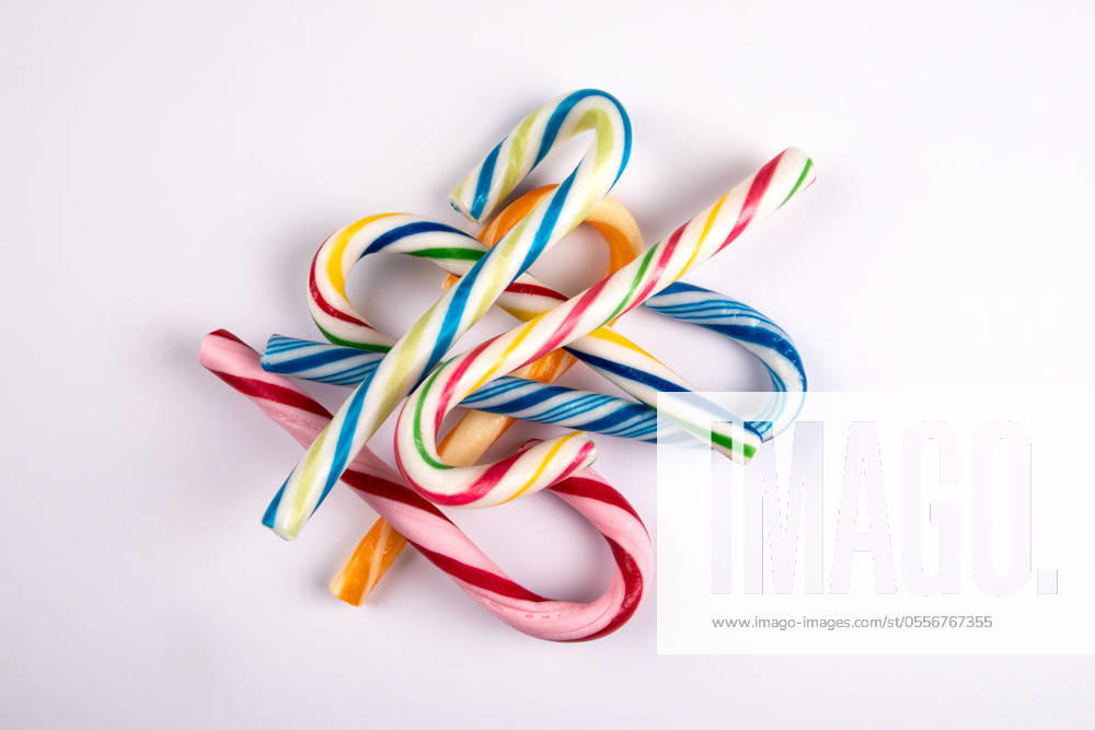 Different colored candy canes in a pile on a white background.