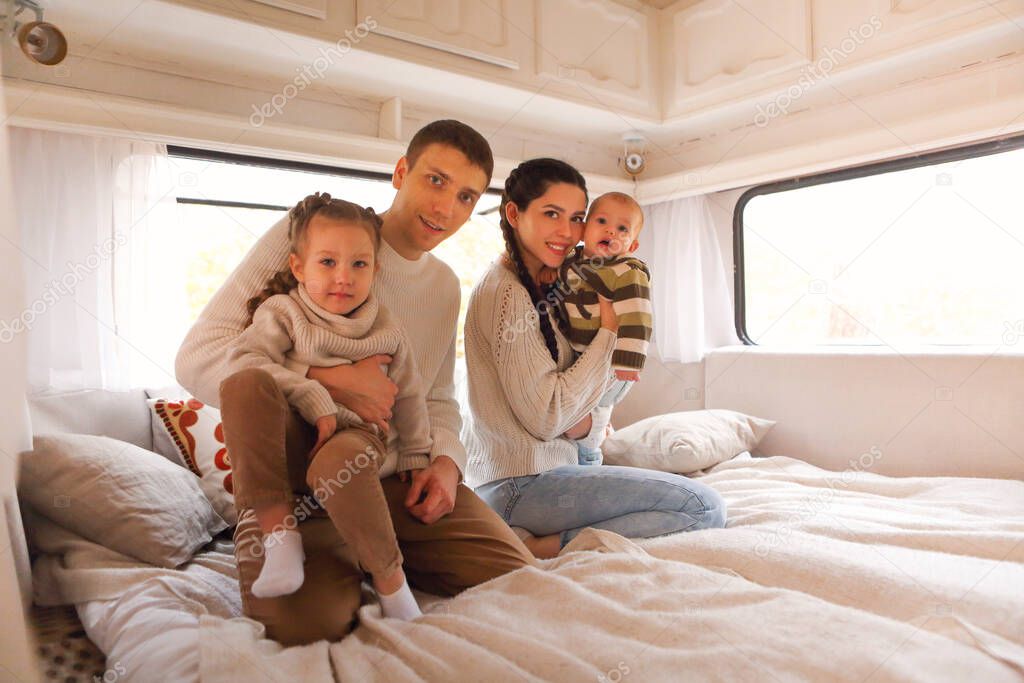 Portrait of the smiling happy family with kids in the house on wheels indoor model released