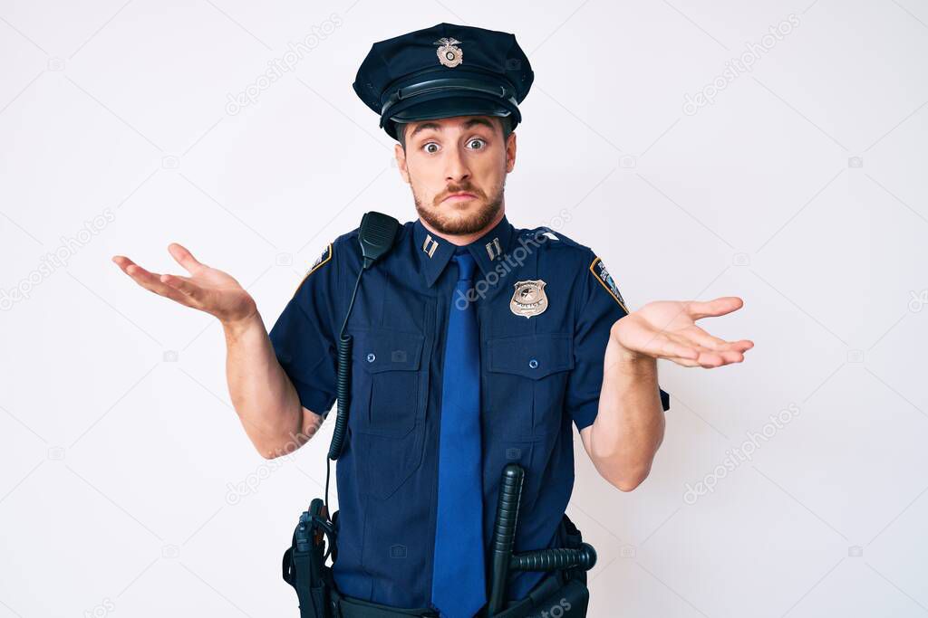Young caucasian man wearing police uniform clueless and confused expression with arms and hands raised. doubt concept. model released