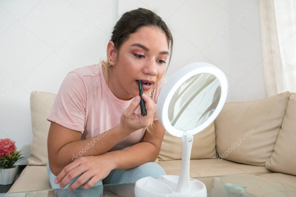 Woman applying lipstick in front of mirror model released