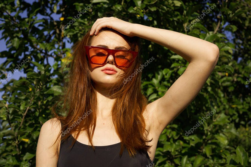 Pretty woman wearing sunglasses green leaves summer model. High quality photo model released