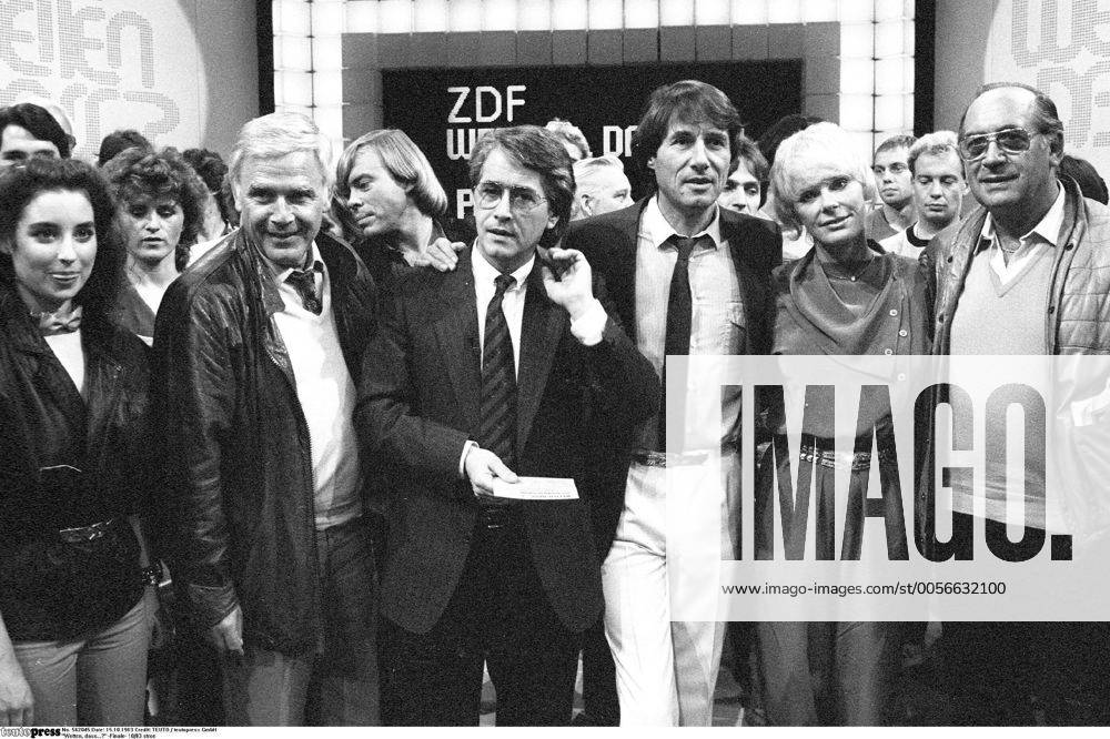 Wetten, dass...? -Finale- 10 83 stroe Isabel Varell, Joachim Fuchsberger, Volker Lechtenbrink (hinten), Frank Elstner, Udo Jürgens und Elke Sommer (v.li.) am 15.10.1983 in Wetten, dass...? (ZDF) aus der Rheingoldhalle in Mainz Deutschland deutsch Mann Schauspiel Schauspieler Moderator Moderation Quizmaster Talkmaster Showmaster Autor Schriftsteller Kino Film TV Fernsehen grauhaarig weißhaarig kurzhaarig seriös Sakko Jackett Krawatte Sängerin Sänger Gesang Musiker Musikerin Musik Schauspielerin Schlußbild Fernsehstudio Studio Fernsehkulisse Kulisse Halle Querformat quer halb stehend stehen lächelnd Lächeln gestikulierend gestikulieren Gestik umarmend umarmen Blacky sw s w schwarzweiß rechts vermutlich Saalkandidat Wolfgang Zimmer
