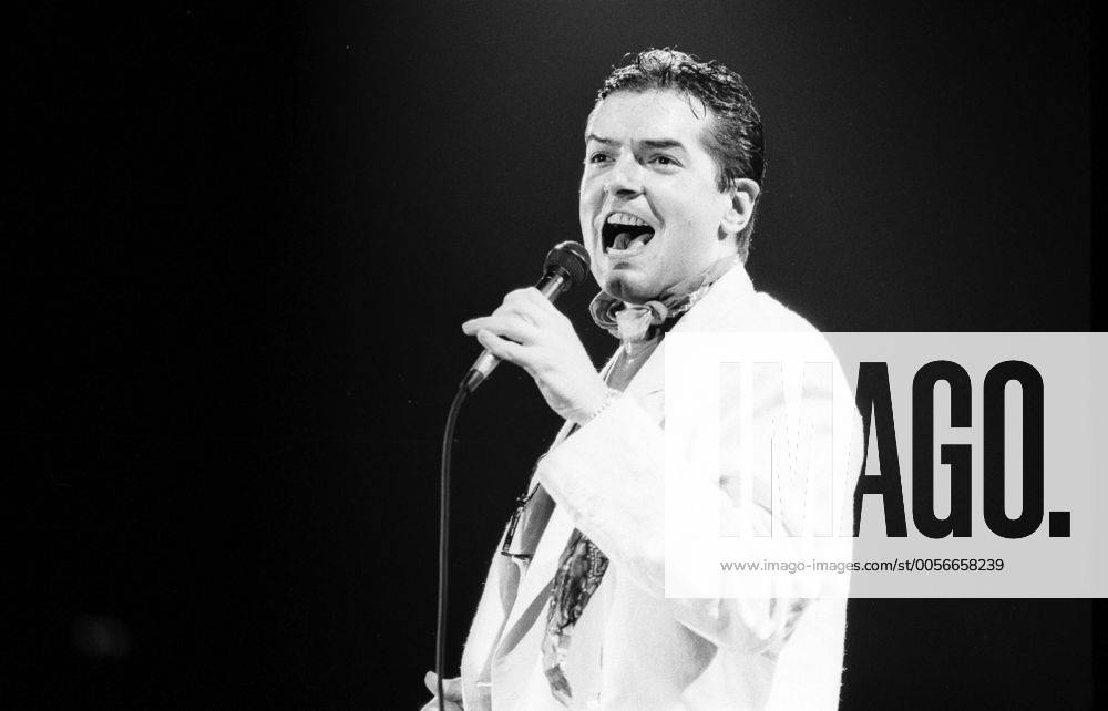 Falco (Sänger, Musiker) 10 86 dar Falco bei einem Konzert im Oktober 1986 Mann Gesang Musik Pop Rock Künstler Österreicher Österreich österreichisch österreichischer Johann Hölzel Bühne Auftritt Show singend Mikro Mikrofon seriös Sakko Jackett Krawatte dunkelhaarig Gelfrisur zurückgekämmt Spot Scheinwerfer halb Singer Music Musician Performance Stage hoch sw
