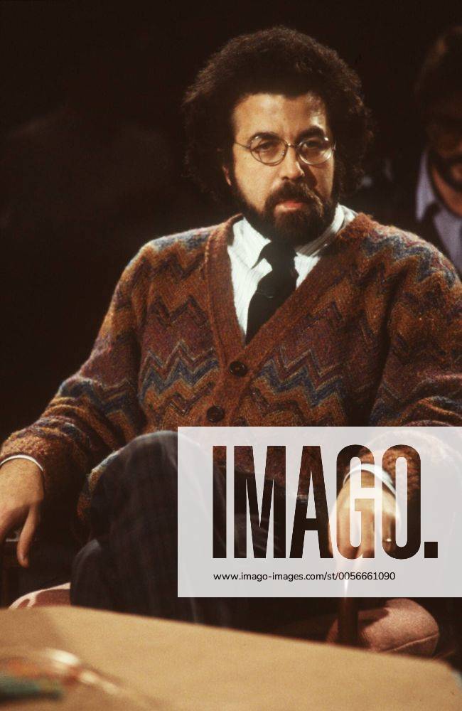 Giuseppe Sinopoli (Dirigent) 12 86 dar Mann Dirigent Musik klassische Klassik Oper dunkelhaarig kurzhaarig Locken Bart Schnäuzer Brille leger Strickjacke Jacke gemustert Hemd Krawatte sitzend Saal Studio dunkel halb hoch nachdenklich zuhörend festhaltend Lehne Stuhllehne