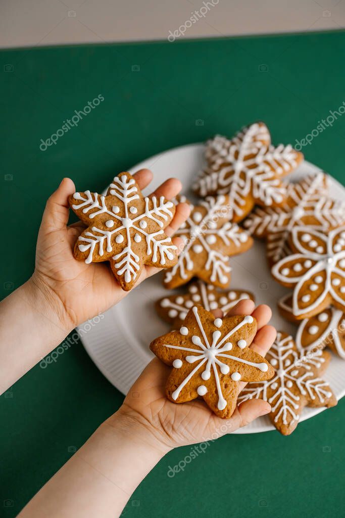 Ginger Christmas cookies in children's hands on the background of the Christmas tree. Top view.