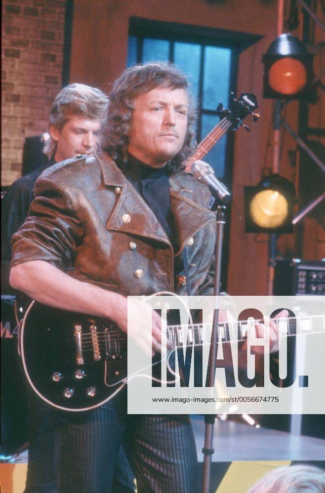 Frank Farian (Komponist, Produzent) 06 87 vZ Mann Musik Produktion Komposition Schlager Pop dunkelhaarig langhaarig Locken leger Pullover Rollkragenpullover Lederjacke stehend Mikrophon Gitarre Bühne Auftritt spielend halb hoch neutral