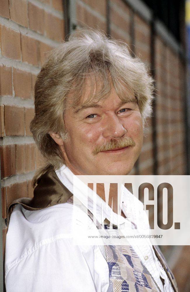Peter Petrel 07 95 her Mann Musik Schlager grauhaarig Schnäuzer leger Hemd Weste hoch Portrait angelehnt Hauswand draußen lächelnd