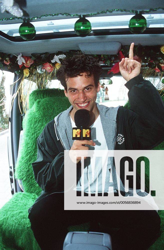 Holger Speckhahn (VJ bei MTV) 04 97 her Mann TV Fernsehen Moderation Musik VJ Videojockey MTV dunkelhaarig leger T-Shirt weiß Jacke sitzend Mikrophon haltend Sessel Bus halb hoch gestikulierend zeigend sprechend