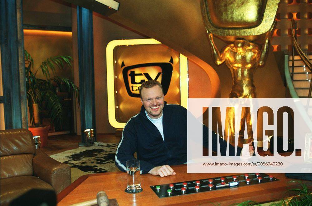 Stefan Raab in tv total (ProSieben) 01 03 pp Mann Moderator TV Fernsehen Moderation Musiker Musik Pop Gesang Sänger Produktion Unterhaltung Show dunkelhaarig kurzhaarig leger Trainingsjacke Sportjacke Shirt sitzend TV-Studio Kulisse Dekoration Logo halb quer sitzend lächelnd Tisch Moderationstisch Pult Glas Wasserglas Fototermin tv total (ProSieben) am 06.01.2003 in Köln