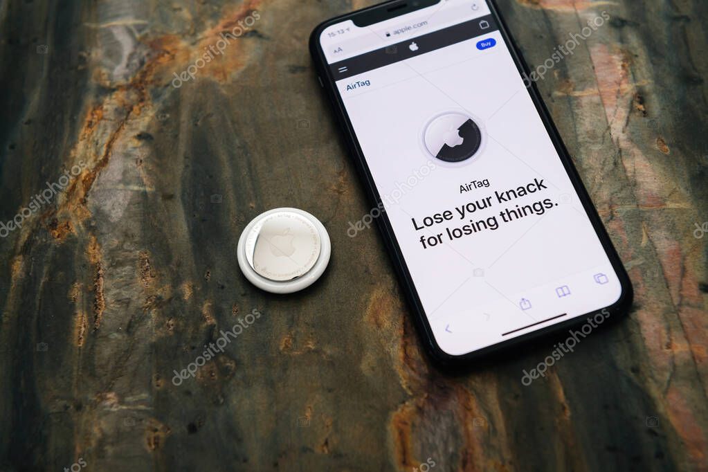 AirTag device next to Apple Computers with its website advertising to product - small device helps people keep track of belongings, using Apple Find My network to locate lost items like keys, wallet, bag