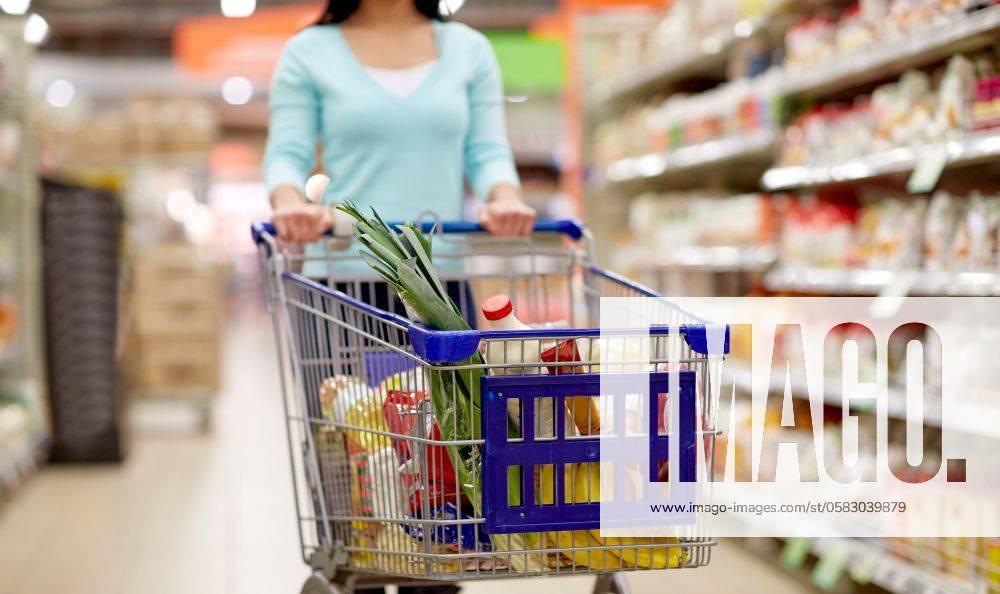 Consumerism and people concept - woman with shopping cart or trolley buying food at grocery store or supermarket. woman with food in shopping cart at supermarket ,model released, Symbolfoto; Konsumismus und Personen Konzept Frau mit Einkaufen Karren Oder Rollwagen kaufend Lebensmittel im grocery Ladengeschaeft Oder Supermarkt Frau mit Lebensmittel in Einkaufen Karren im Supermarkt ,model released, Symbolfoto ING_33594_221633 RECORD DATE NOT STATED