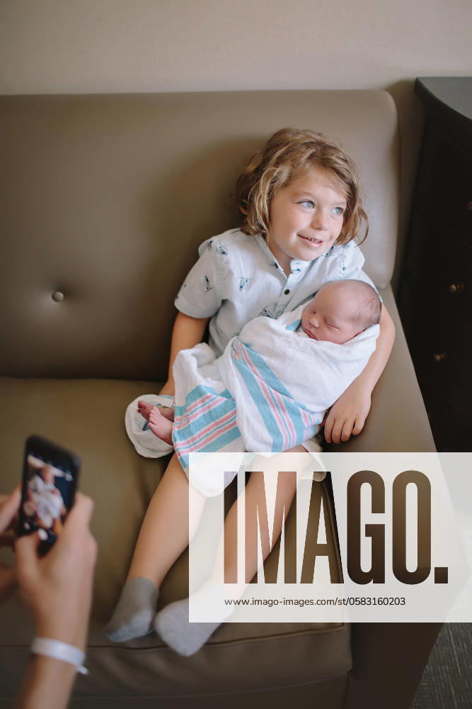 Young boy sitting on a couch holding a newborn baby while someon Atlanta, Georgia, United States CR_RCYA240618-1462814-01 ,model released, Symbolfoto
