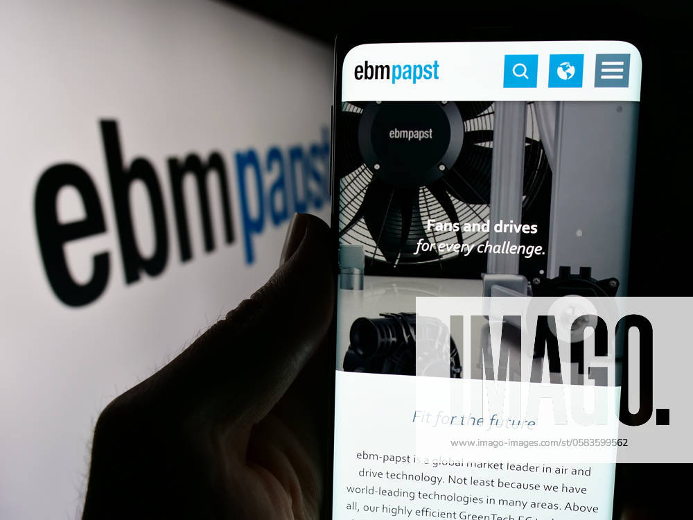 Person holding cellphone with webpage of German electric motor company EBM-Papst Gruppe. Stuttgart, Germany - 04-13-2024: Person holding cellphone with webpage of German electric motor company EBM-Papst Gruppe in front of logo. Focus on center of phone display.