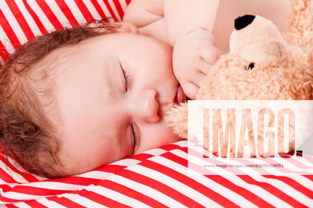 Kleines süßes baby kleinkind neugeborenes schläft mit teddy bär im arm auf einer decke