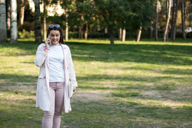 Young woman having a conversation on her smartphone, A young woman having a conversation on her smartphone outdoors in a park on a sunny day. model released