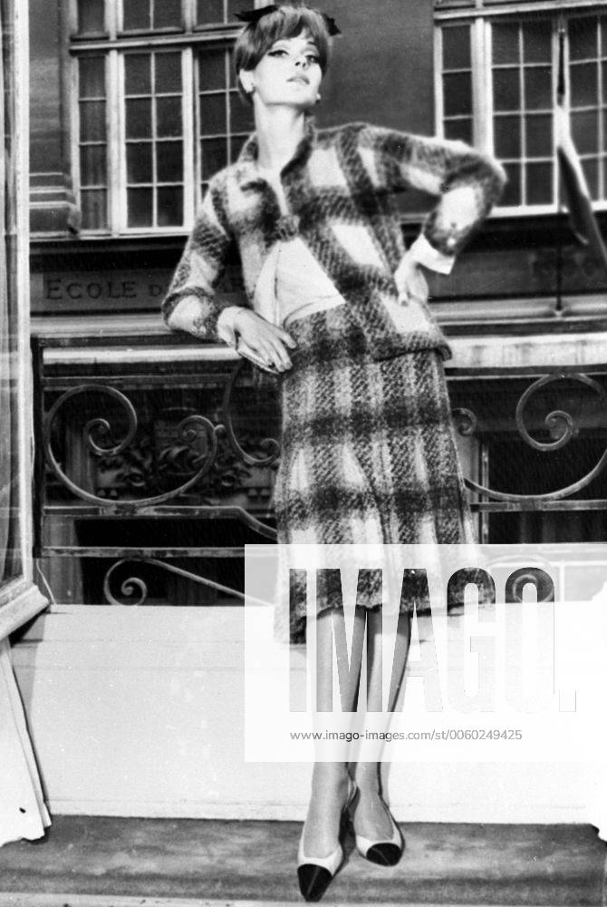 IMAGO ICONS: Coco Chanel Autumn Winter season from Coco Chanel . Chanel s winter suits featured many vivid colour combinations . This model shows her new pelated skirt topped by a slender straight jacket is in a blanket plaid in a vivid salmon and green combination , worn with a pink silk blouse . 29th July 1964 UnitedArchives01230264