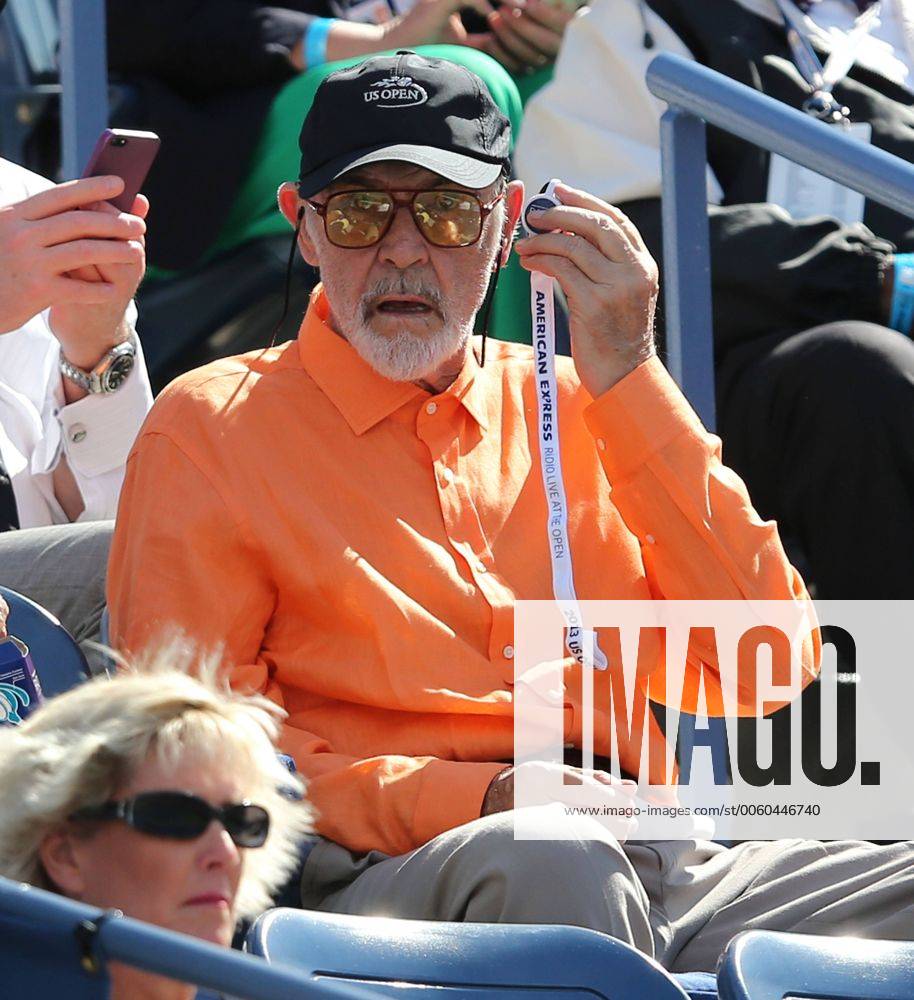US Open 2013, USTA Billie Jean King National Tennis Center, Flushing Meadows, New York, ITF Grand Slam Tennis Tournament . Schauspieler Sean Connery auf der Zuschauer Tribüne,klemmt sich ein kleines Transistorradio an sein Ohr,Einzelbild,Halbkörper,Hochformat, VIP,Ehrengast,Feature,