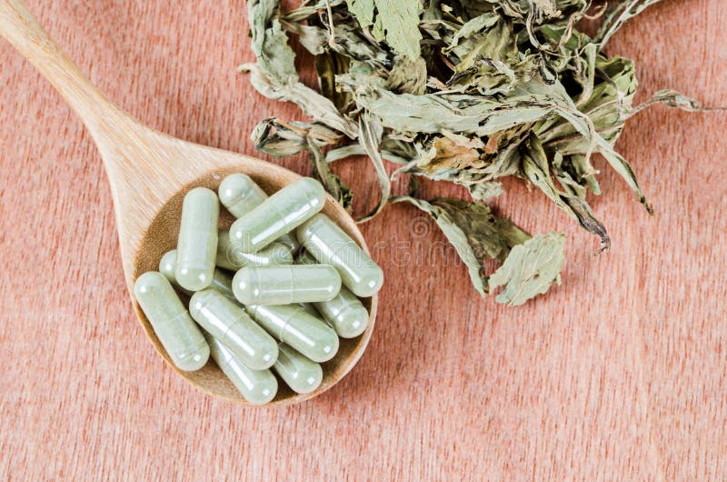 Herb medical capsules in wooden spoon with dry leaves herb, Herb medical capsules in wooden spoon with dry leaves herb on wooden background
