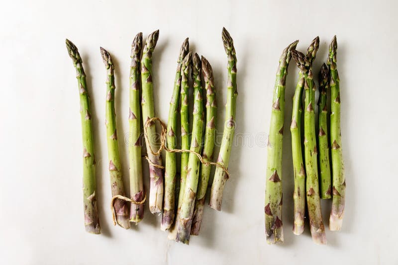 Bundle of green asparagus, Bundle of raw organic green asparagus with thread over white marble background. Flat lay, space