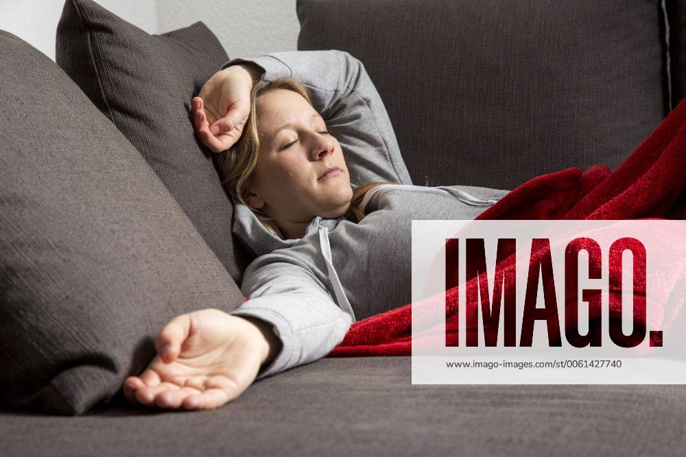 Junge Frau fühlt sich unwohl, entspannt auf einem Sofa