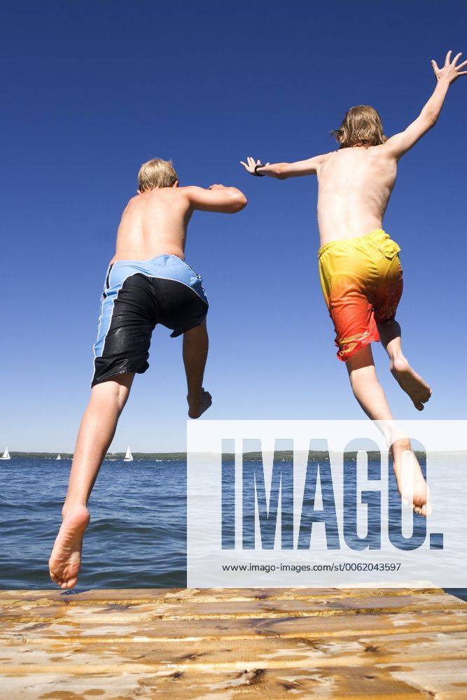 Two boys (9 & 12 years old) jumping off dock into lake, Sylvan Lake, Alberta, Canada. acp05713 RoyxOoms