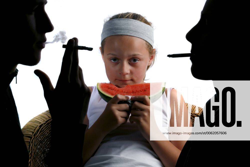 A Girl Eating a Watermelon with two adults smoking either side of her.