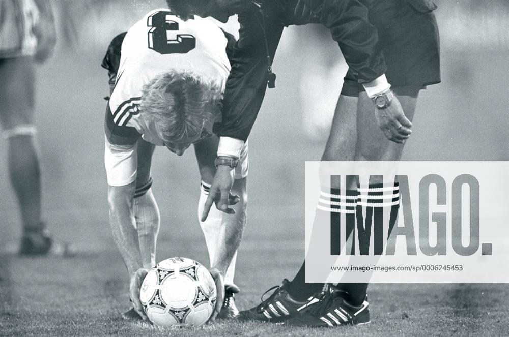WM 1990, Hochspannung beim Finale in Rom - Andreas Brehme (BR Deutschland) legt sich besonders sorgfältig den Ball für den entscheidenden Elfmeter zurecht, denn Schiedsrichter Edgardo Codesal Mendez (Mexiko) will es ganz genau wissen o0 Gestik Körperteile Arm Hand Spannung BRD