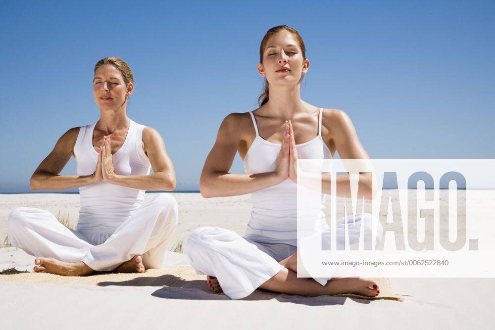 Two women exercising yoga on beach model released WESTF04968