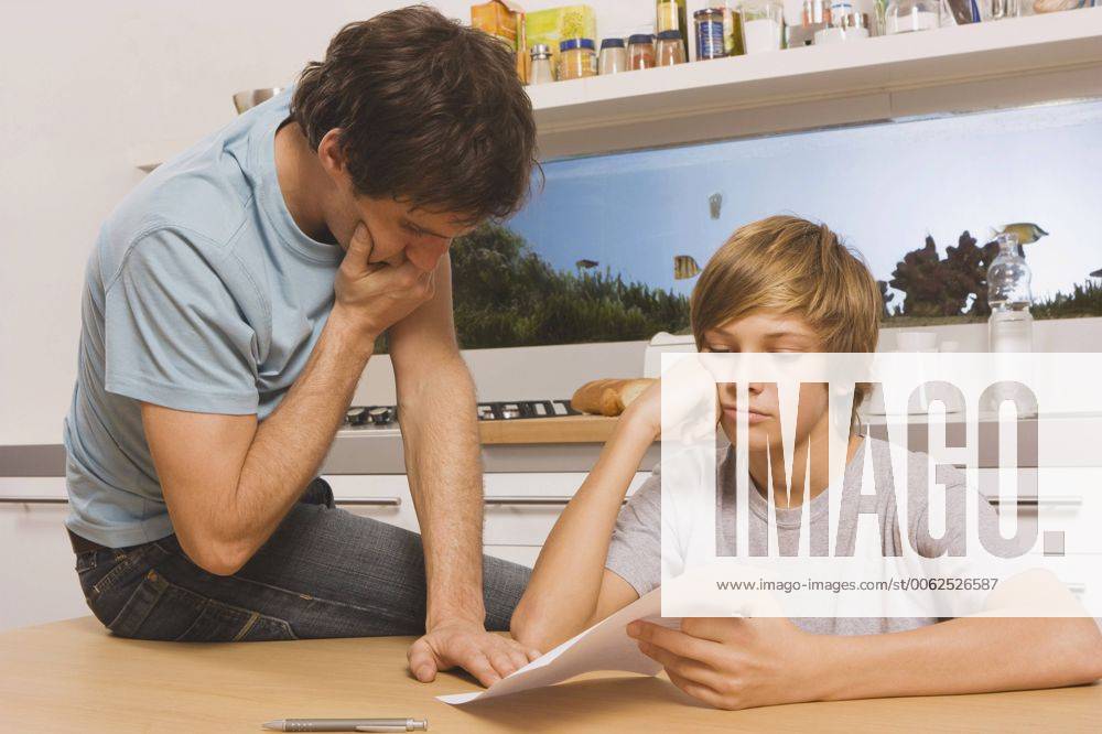 Father and son (13-14) looking at report card, hands to chin model released WESTF11057