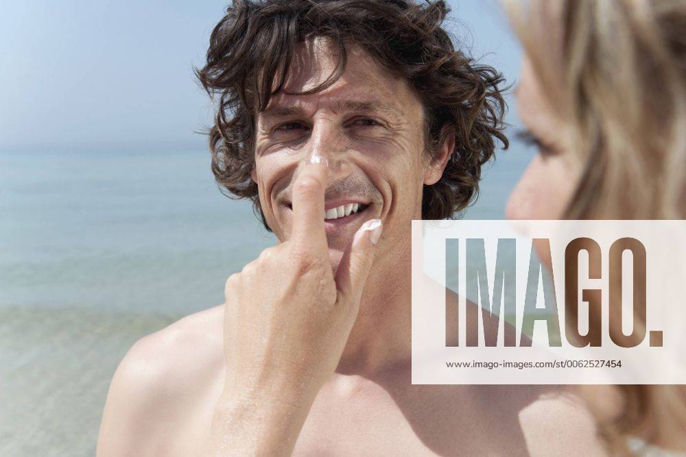 IMAGO Creative, Jahreszeit Sommer, Sonnenschutz Spain, Mallorca, Woman applying suncream on man s nose model released WESTF12688