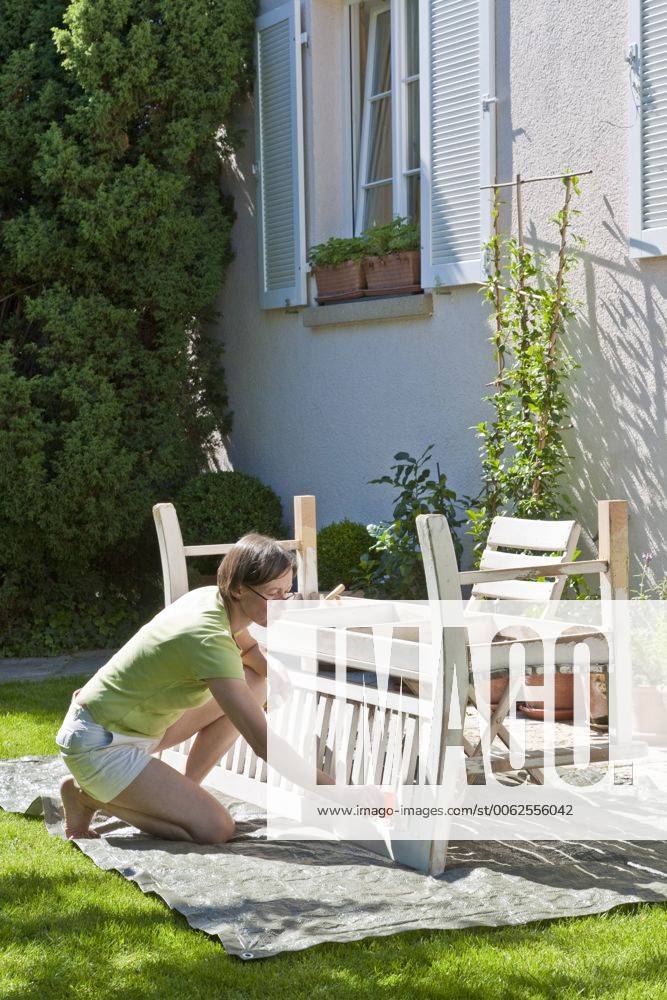 Germany, Stuttgart, woman painting bench in garden model released property released WDF000868