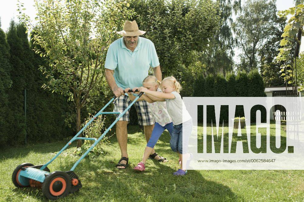 Germany, Bavaria, Grandfather with children mowing lawn model released property released RNF001004