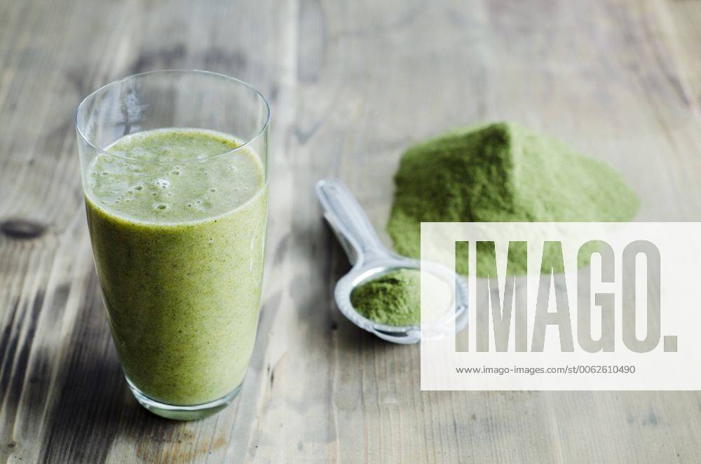 Moringa powder on spoon and wooden table and glass of moringa smoothie CZF000133
