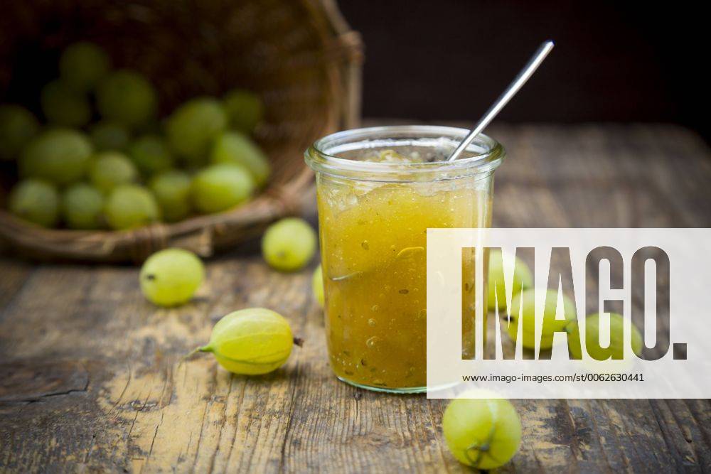 Jar of gooseberry jam, basket and organic gooseberries on dark wood LVF001572