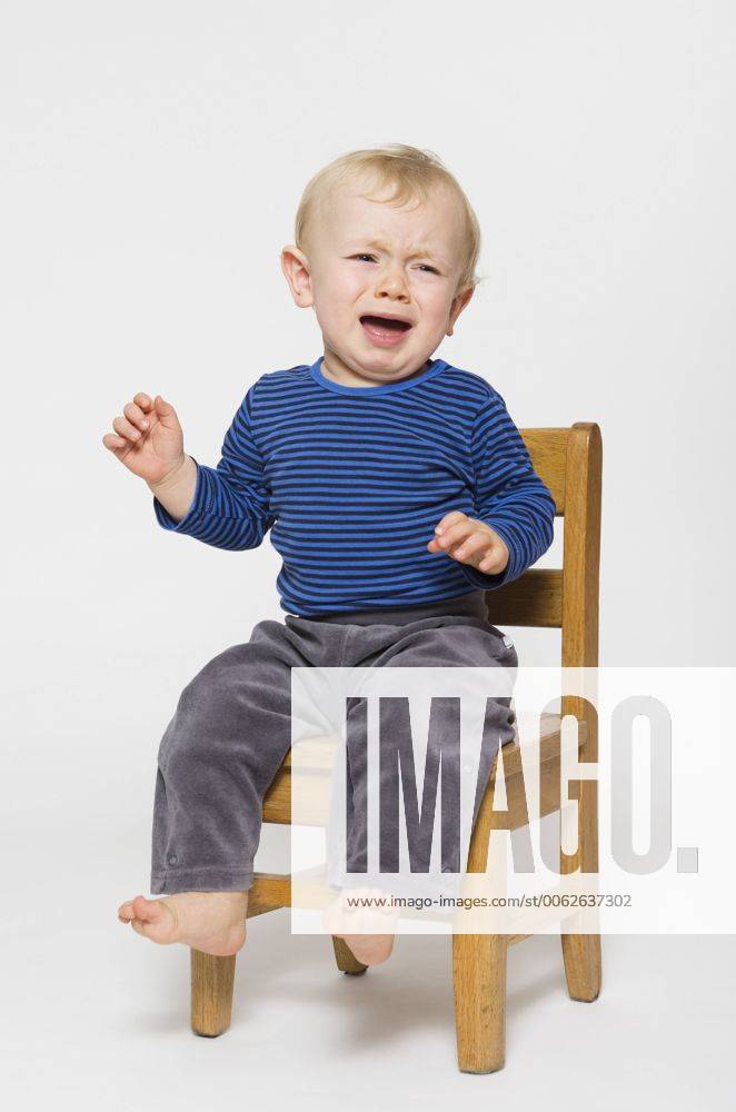 Crying baby boy sitting on chair, studio shot model released MUF001378