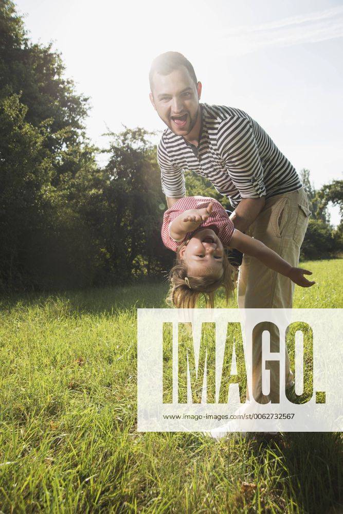 Father playing with his little daughter on a meadow model released Symbolfoto UUF001521