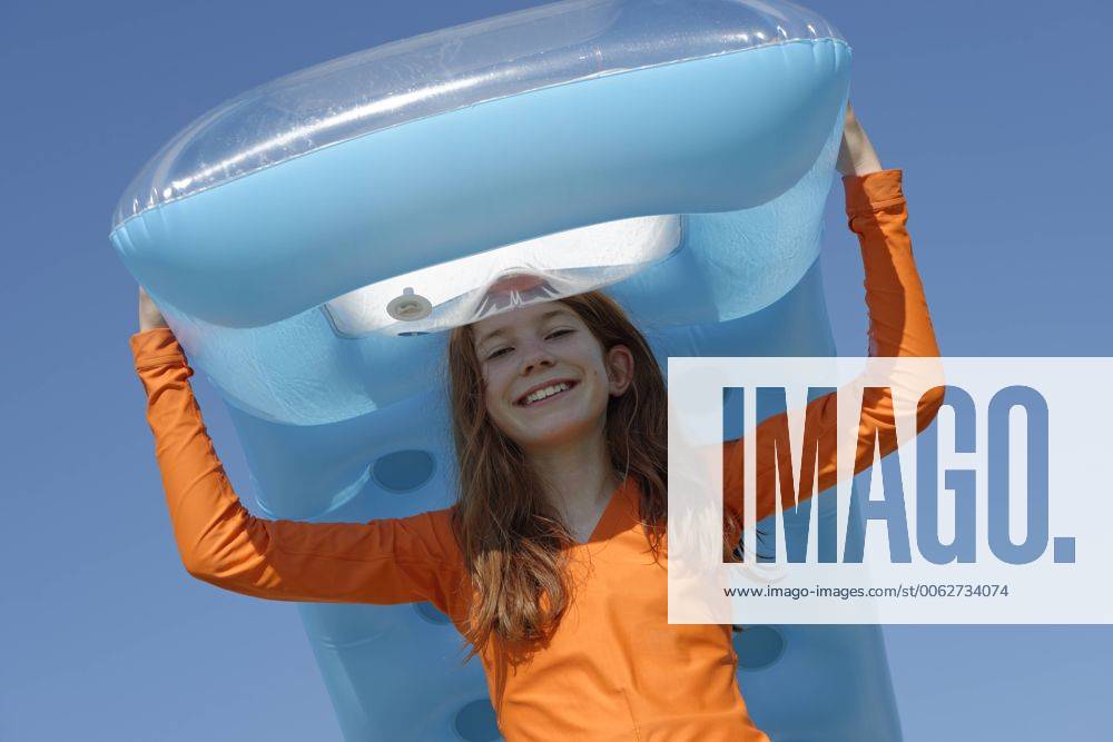 IMAGO Creative, Jahreszeit Sommer, Sonnenschutz Portrait of smiling girl carrying air mattress on her head wearing sun protection longsleeve model released Symbolfoto LBF000834