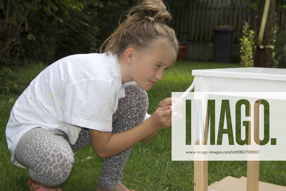 Little girl painting wooden table with white varnish model released Symbolfoto YFF000224