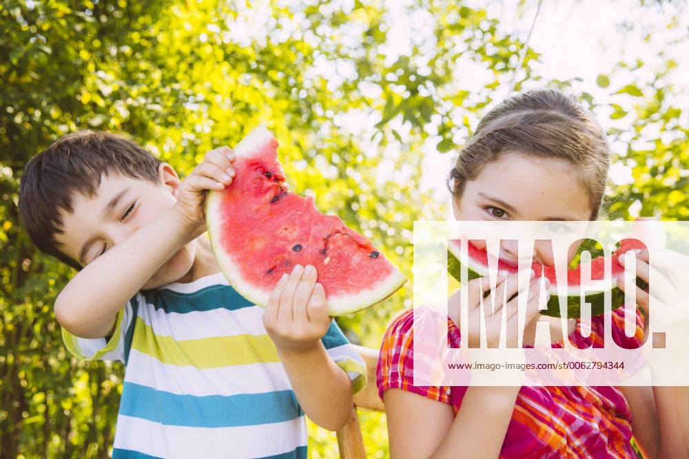 Children eating slices of watermelon in garden model released Symbolfoto property released MFF001285
