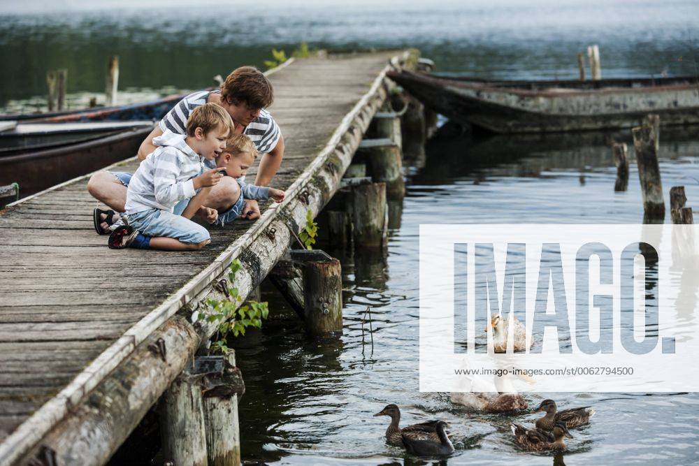 Germany, Rhineland-Palatinate, Laacher See, father with two sons on jetty feeding ducks model released Symbolfoto PAF000924