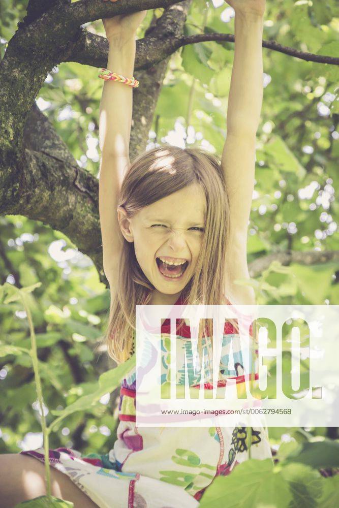 Portrait of laughing little girl climbing on a tree in the garden model released Symbolfoto SARF000784