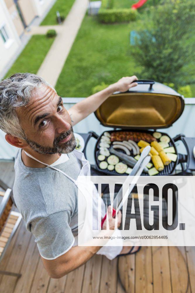 Man barbecuing on his balcony model released Symbolfoto property released MBEF001273