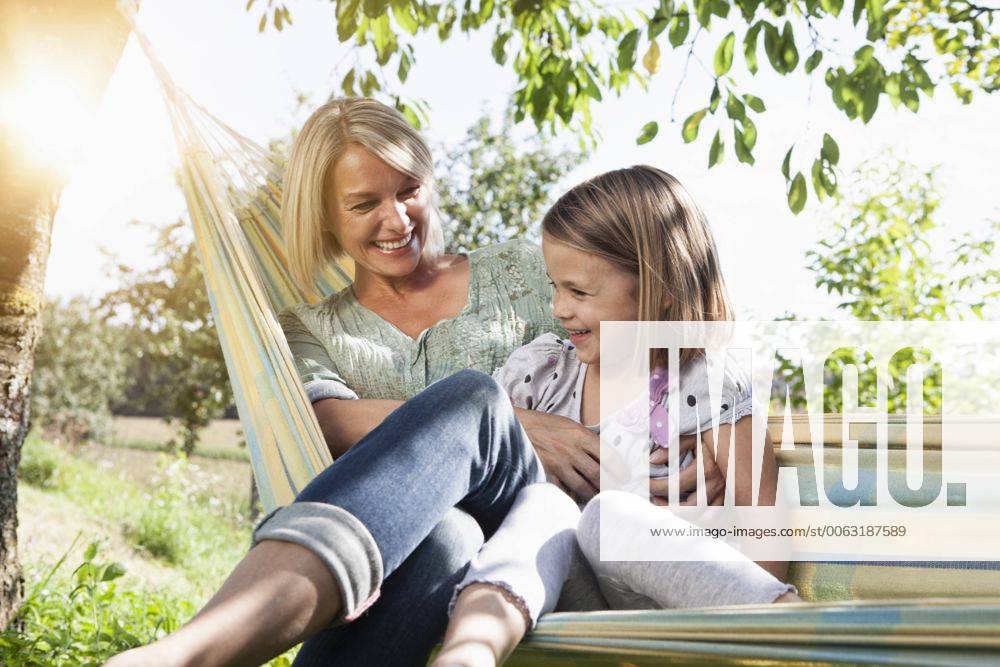 Happy mother and daughter sitting in hammock model released Symbolfoto RBF001964