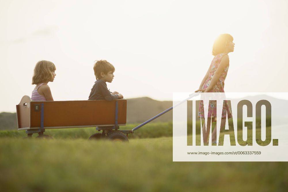 Girl pulling trolley with little boy and girl sitting inside model released Symbolfoto MVC000134