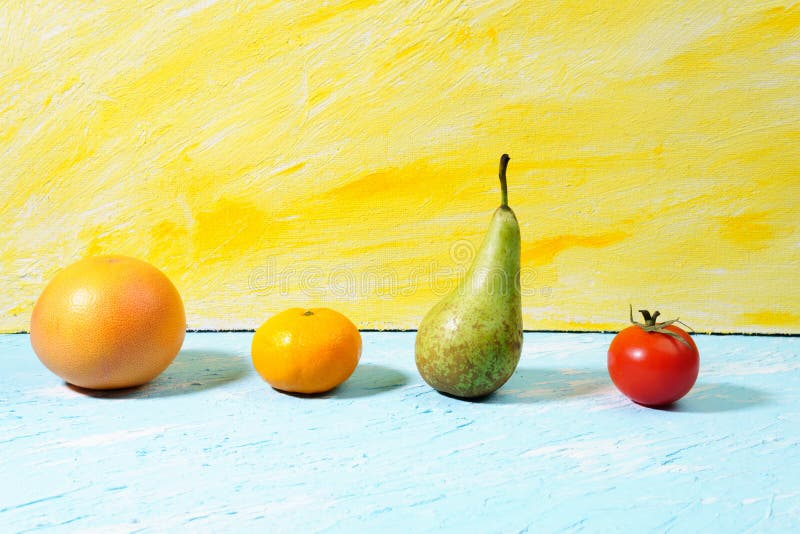 Vegan food. Healthy diet concept. Fruits, vegetables, blue yellow background. pear, grapefruit, tangerine, tomato, Creative composition made of fruits and vegetables on blue background. blue yellow color copyspace