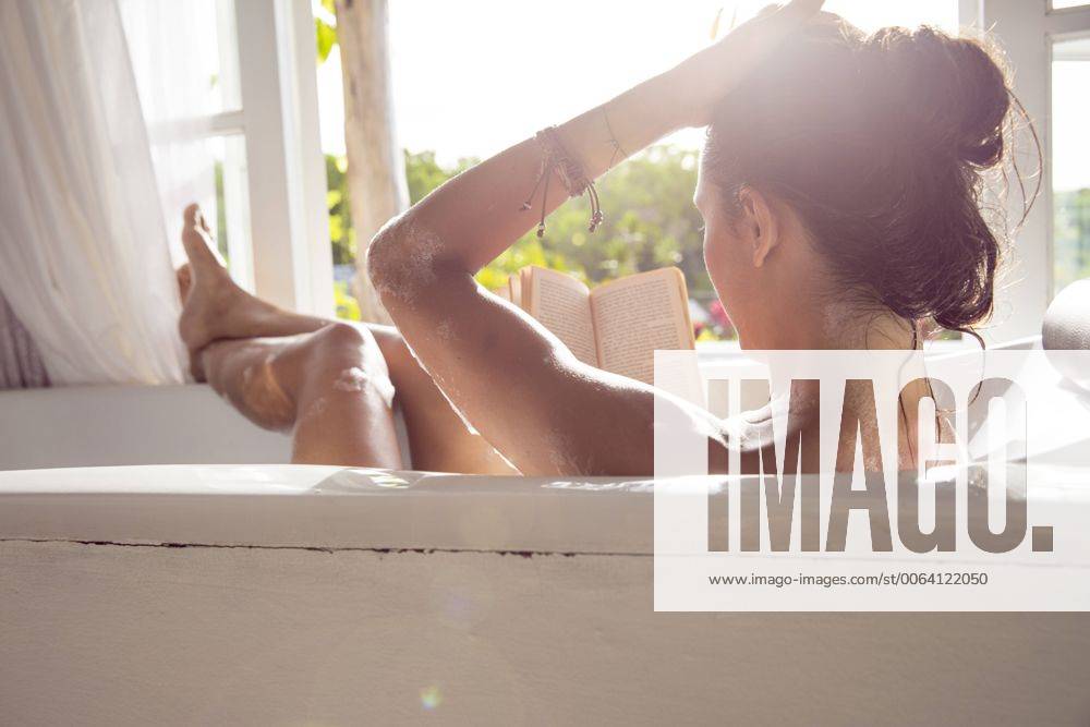 Woman relaxing in bathtub reading book model released Symbolfoto property released MBEF001334