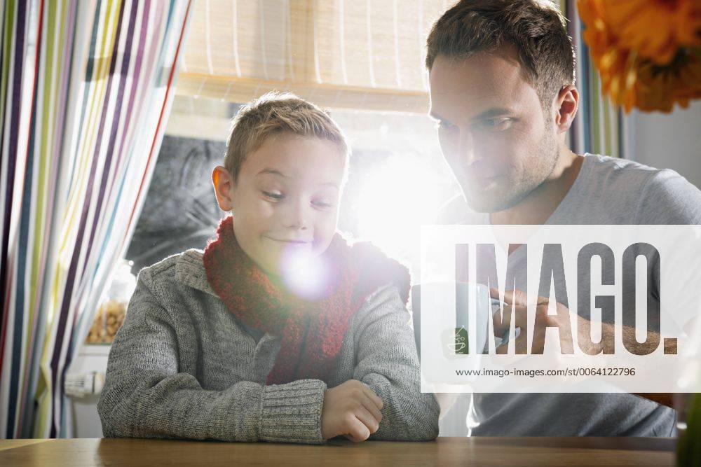 Boy having a cold sitting in the kitchen with his father model released Symbolfoto property released PDF000743