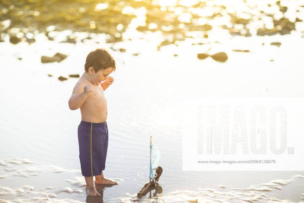 Boy playing with a toy wooden boat in the water model released Symbolfoto ZEF003421