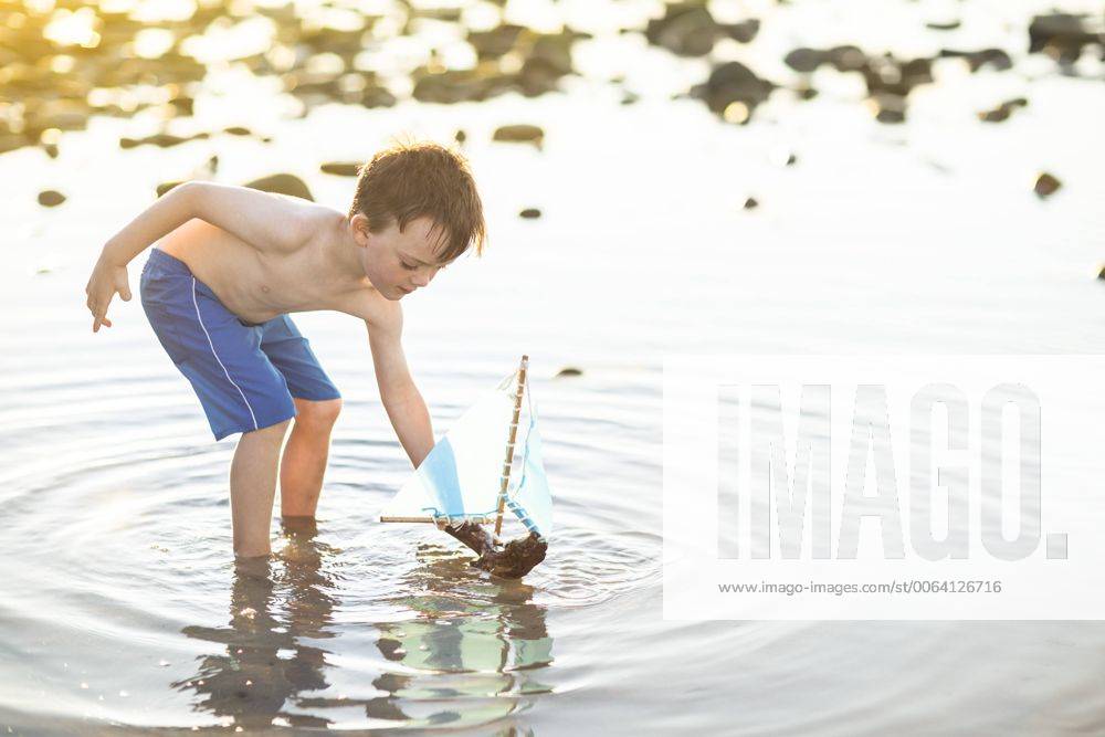 Boy playing with a toy wooden boat in the water model released Symbolfoto ZEF003423