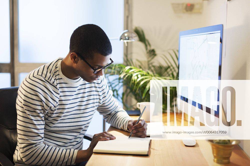 Young creative man sitting at desk writing in his notebook model released Symbolfoto property released EBSF000541